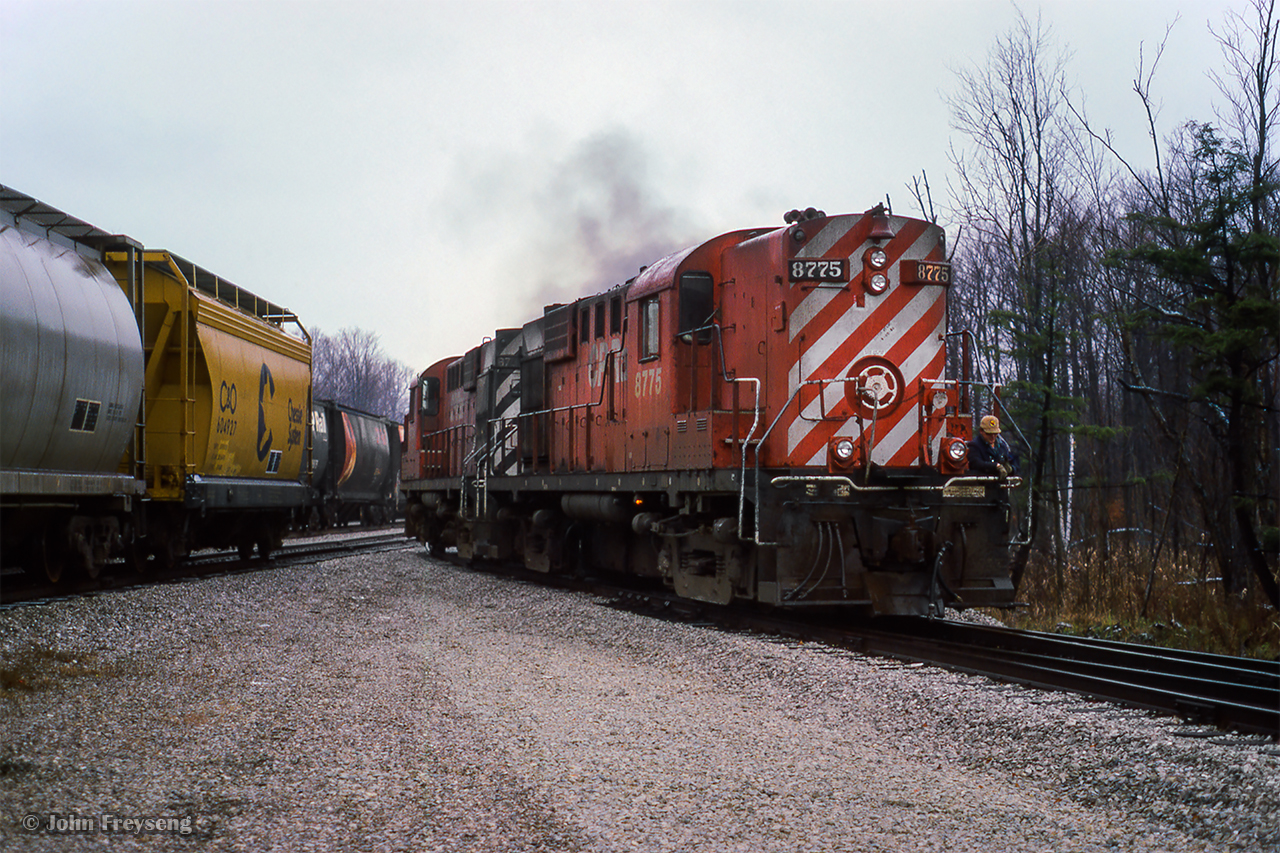 CP's Guelph Jct yard job is seen moving around the west end of the wye as their prepare to build their train for Waterdown North.  The hoppers at left will be delivered by the pair of MLW RS18s to Barnes Environmental International.Scan and editing by Jacob Patterson.