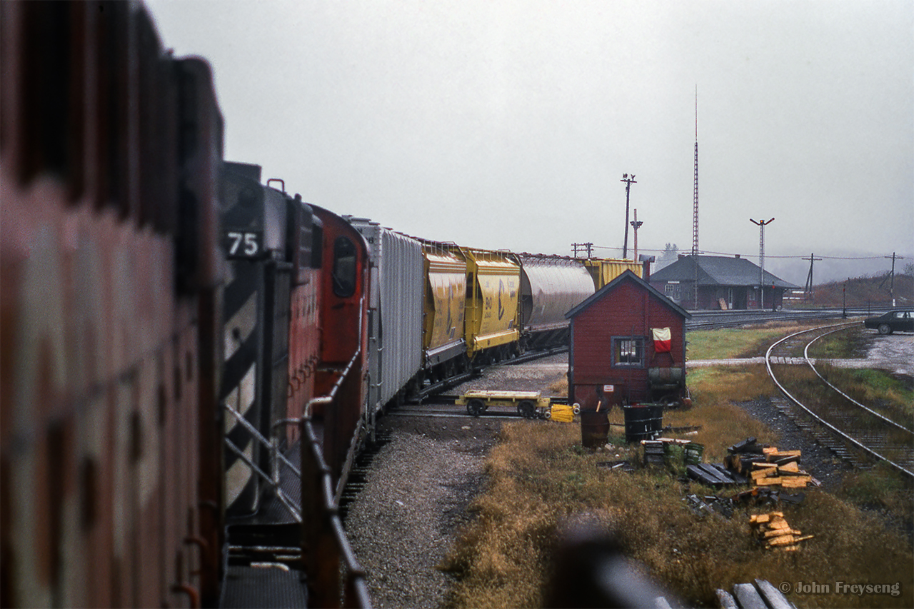 After making up their train, the Guelph Junction road switcher has pulled out the west end of the junction, shoved east to clear the Goderich Sub switch, and departs for Barnes Environmental International at Waterdown North. Looking back, the short train, led by a pair of MLW RS18s, swings around the curve with the Guelph Junction station in the distance.

Scan and editing by Jacob Patterson.