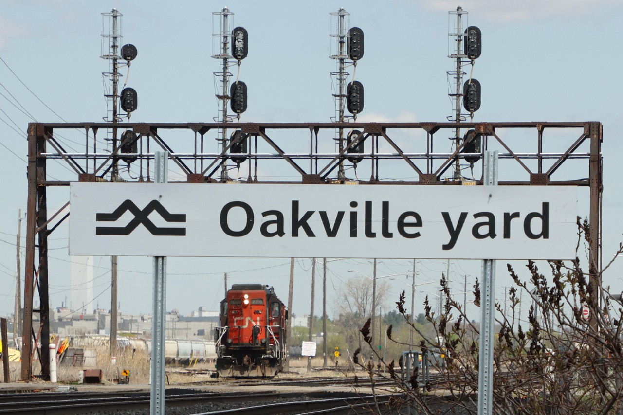 The new Metrolinx station name sign at Oakville Yard provides the frame for L554 with CN 7068 CN 4936 waiting to get out of the Yard and head for the Cement lead with a tank and a hopper today.