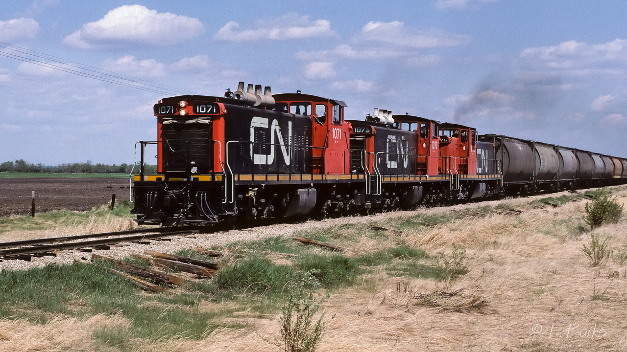 There were 4 trains every week on the Coronado at this time. Peddling grain cars and bringing the loads back to Edmonton. 2 of those 4 would also have fuel tanks in the consist (destined for the cold lake air base). It looks to be a solid train of grain loads, but, it is possible that the front few CN hoppers may have had a different purpose. The late 80's was the last hurrah for GMD-1's on the Coronado Sub. GP9's also. By 1990, the GP38-2's owned the rail, on occasion, a GP-9 would trail as a helper, never leading. This did not last long either. The 1070 at the rear seems to have its CN noodle on the long hood painted just a little lower than the others. Photo taken at mile 26.6 on Saturday, just after lunch.