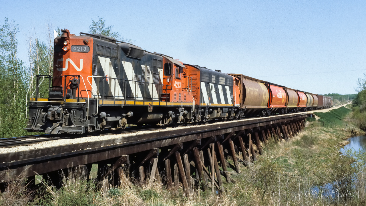 A short train returning to Edmonton at 10:30 on a clear Saturday morning. The empty sailboat in the middle of the train will have had farm machinery as a load. That was the 9173 trailing. This photo taken with Ektachrome 200asa film, an infrequent stray away from Kodachrome.