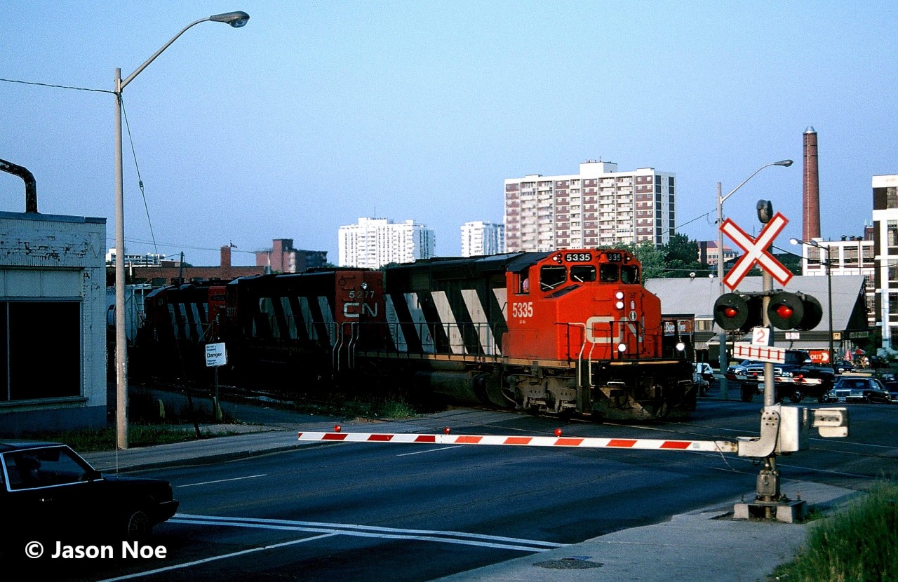 It’s just after 20:00 and CN 421 is emerging from the shadows as it crosses King Street in Kitchener, Ontario heading for London. Powering the evening westbound are SD40-2(W)’s 5335 and 5277, as well as 4128, which was either for Stratford or London.