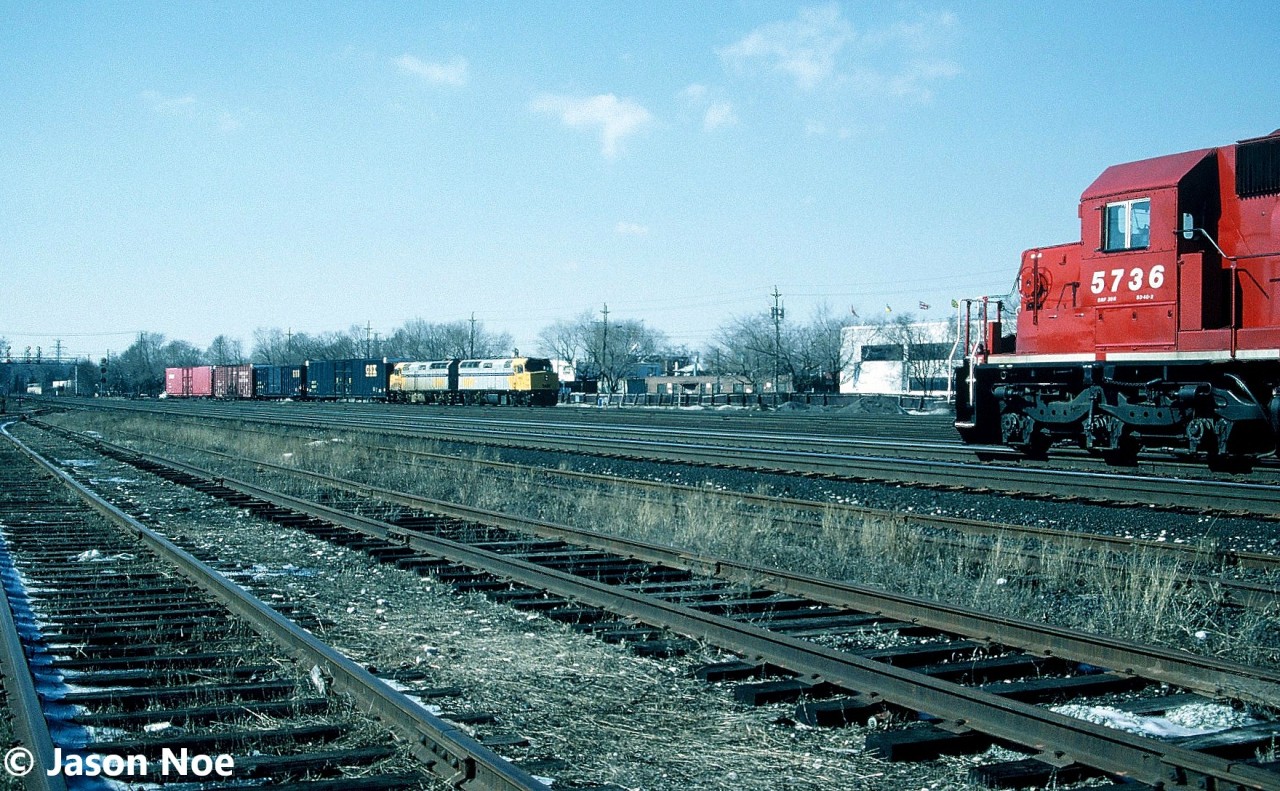 A CP westbound train is viewed waiting to depart Lambton Yard near West Toronto, Ontario on the Galt Subdivision with a trio of SD40-2’s that included; 5736, 672 and SOO Line 788. At the same time, a short eastbound train continues to Toronto Yard with leased VIA Rail F40PH-2’s 6453 and 6454 for power. At the time, CP Rail was leasing nine F40PH-2’s from the passenger carrier to assist with their motive power shortage. They were mainly used on local jobs as well as mainline 900 series trains that operated within the province.