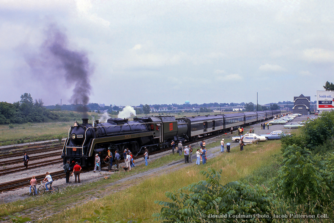 During a Toronto - Niagara Falls excursion, CNR 6060 and its train have just returned from the wye at Yager, and are seen backing down the platform at the falls.  The empty land beyond the train once held steam era service facilities and the coach yard, no longer needed by this time.

Donald Coulman Photo, Jacob Patterson Collection slide.