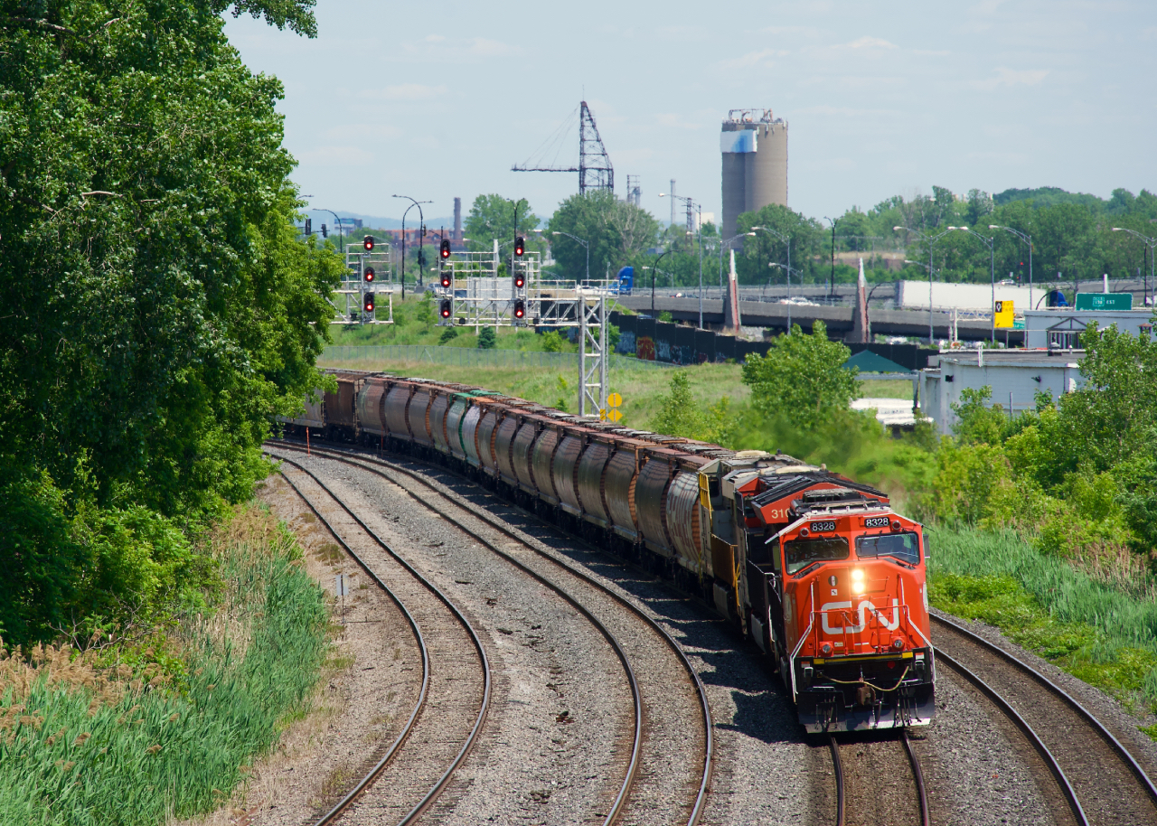 CN 527 has fresh rebuild CN 8328 leading and a string of MGLX hoppers up front as it rounds a curve a bit past Turcot Ouest.