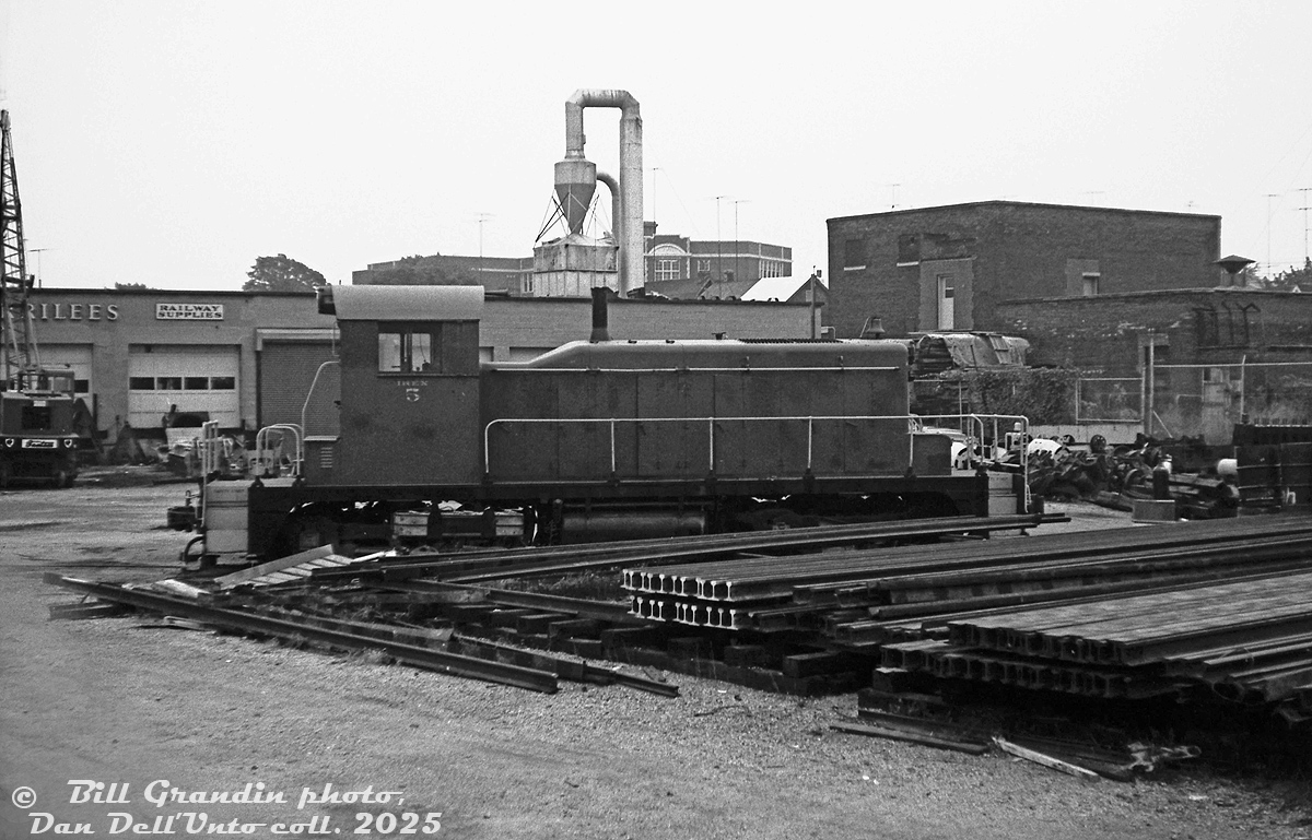 Having a peep through the fence into the Andrew Merrilees railway supply yard in West Toronto, IREX SW1 5 (former D&LW 433, later to Stelco 5) sits parked inside amid sections of rail and other supplies for sale. Their main shop and office building is visible in the background.

A longtime resident of the West Toronto "Junction" area, Andrew Merrilees Ltd (formed 1946) sold new and used railway equipment and supplies including rails, and track components. They also bought, sold and leased small locomotives for industrial use, and had a siding off CP's MacTier Sub. Their own reporting marks were AAMX, but they formed a US subsidiary calle Industrial Railway Equipment (IREX). The company closed down their West Toronto yard in the Summer of 2016 and the property was sold off for other uses.

Bill Grandin photo, Dan Dell'Unto collection negative.