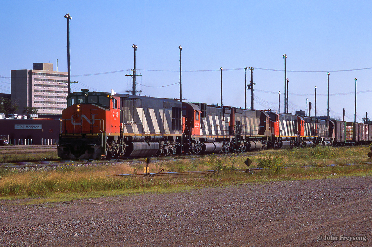 A westbound CN freight, headed up by six MLW/BBD locomotives, is seen passing through downtown Moncton.

Scan and editing by Jacob Patterson.