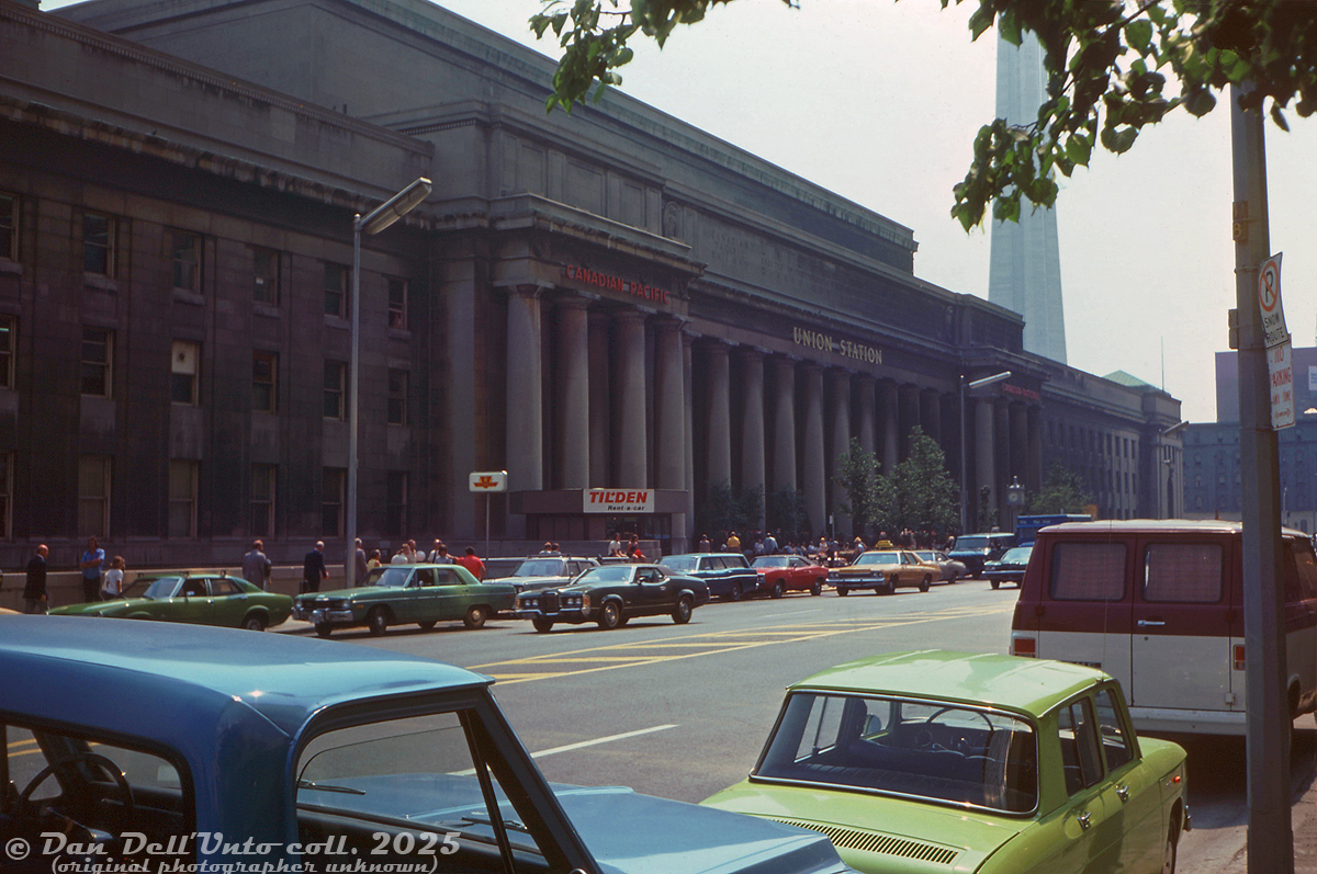 A streetside view of Toronto Union Station along Front Street back in the summer of 1975, back when you could still catch CP's The Canadian or CN's Super Continental out of downtown Toronto, catch the Turbo Train to Montreal eastbound, go inside to the Maple Room or the Oak Room for a meal, rent a car from Tilden, catch a TTC "Red Rocket" downstairs or mosey on over to CP Hotel's Royal York across the street. Steam heating to Union, the Royal York, John Street Roundhouse and many nearby downtown buildings was still provided by the Toronto Terminal Railway's Central Heating Plant.Note the dial "Canadian Pacific" and "Canadian National" ownership lettering above each entrance. A new attraction in the form of the CN Tower is nearly complete in the distance, not set to open for another year. A blue Toronto Star delivery van is parked among the sea of colourful 70's land yachts and American iron out front, making the daily delivery of those old paper information things called newspapers.Original photographer unknown, Dan Dell'Unto collection slide.