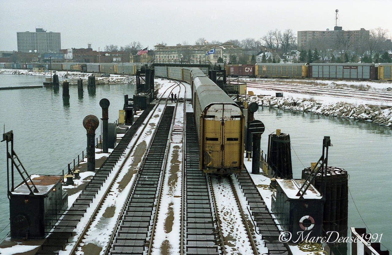 While my interest in Rail photography only spans about the last 13 years, my interest in Great Lakes Shipping began way back in 1982. This photo of auto racks being loaded onto the CN Ferry PHYLLIS YORKE combines the two interests. on this particular day my buddy Duncan White called and asked if I would like to take a ride on the CN ferry to Port Huron and back as the lake freight McKEE SONS was being towed up the St. Clair River that day but had docked in Port Huron due to weather and this would be our best chance to see it. Dunc's good friend Captain Bob Campbell was working on the PHYLLIS YORKE that day and welcomed us aboard. Anyone familiar with the Sarnia are may know that there is only one way traffic under the Bluewater Bridges but not many know why. Here's a brief synopsis why as it involves Captain Campbell. In the early morning hours of June 5, 1972, the down bound Steamer PARKER EVANS collided with the up bounder SYDNEY E. SMITH Jr., just south of the Bluewater Bridge. That night Captain Campbell and deckhand Bill Chadwick were working on the Pilot Boat SALLY M and were stationed at the nearby Purdy Fisheries dock. Upon hearing the collision and the resulting whistle blasts from the now heavily listing and sinking SMITH, Captain Campbell immediately departed the dock, maneuvering the SALLY M alongside the SMITH rescued evacuating crew members from the SMITH. All 31 crew members were safely evacuated including the Master of the SMITH, Captain Arn Kristensen(last man off). For their heroic efforts Captain Campbell and deckhand Chadwick received commendations from the United States Coast Guard. Since this accident there is now only one way traffic between the Black River entrance and buoys 1 & 2 in the Lake Huron Cut. There is a Commemorative plaque south of the bridges on the Canadian side recognizing this event.