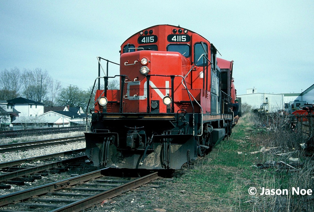 CN train 580 with GP9RM 4115 is viewed lifting a loaded bulkhead car from the Babcock & Wilcox facility on the Fergus Subdivision. The crew had just set-off an empty flat at the plant and will shortly depart to continue switching other industries on the Galt Industrial Spur in Cambridge. To the left of the unit is the Fergus Subdivision main which ended near the CN Finnigan sign at Hespeler Road, and the CP Waterloo Subdivision.