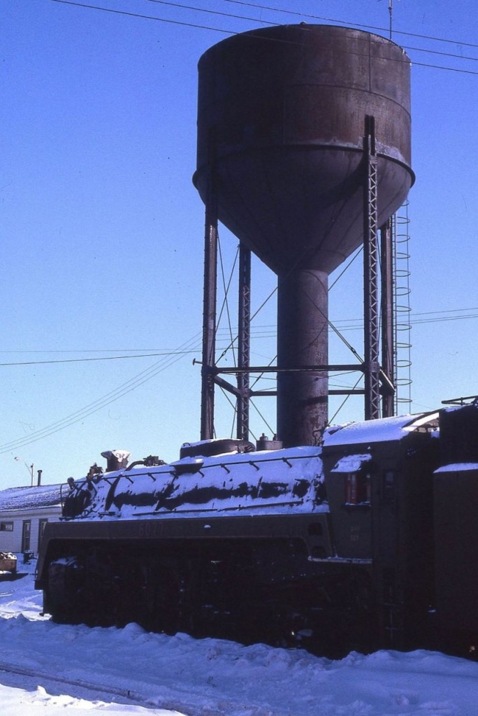 CN 6077 as it arrived at Capreol, Ontario in February 1967.  The water tank seems to be saying: "Hello again 6077!!!  It has been a long time since I last filled your tank.  But what is with that small square thing behind you?? What happened to your vanderbilt tender?"

6077 was quickly taken inside the roundhouse where it was repainted and refitted with a proper vanderbilt tender (from 6136??) in preparation for display in Prescott Park.