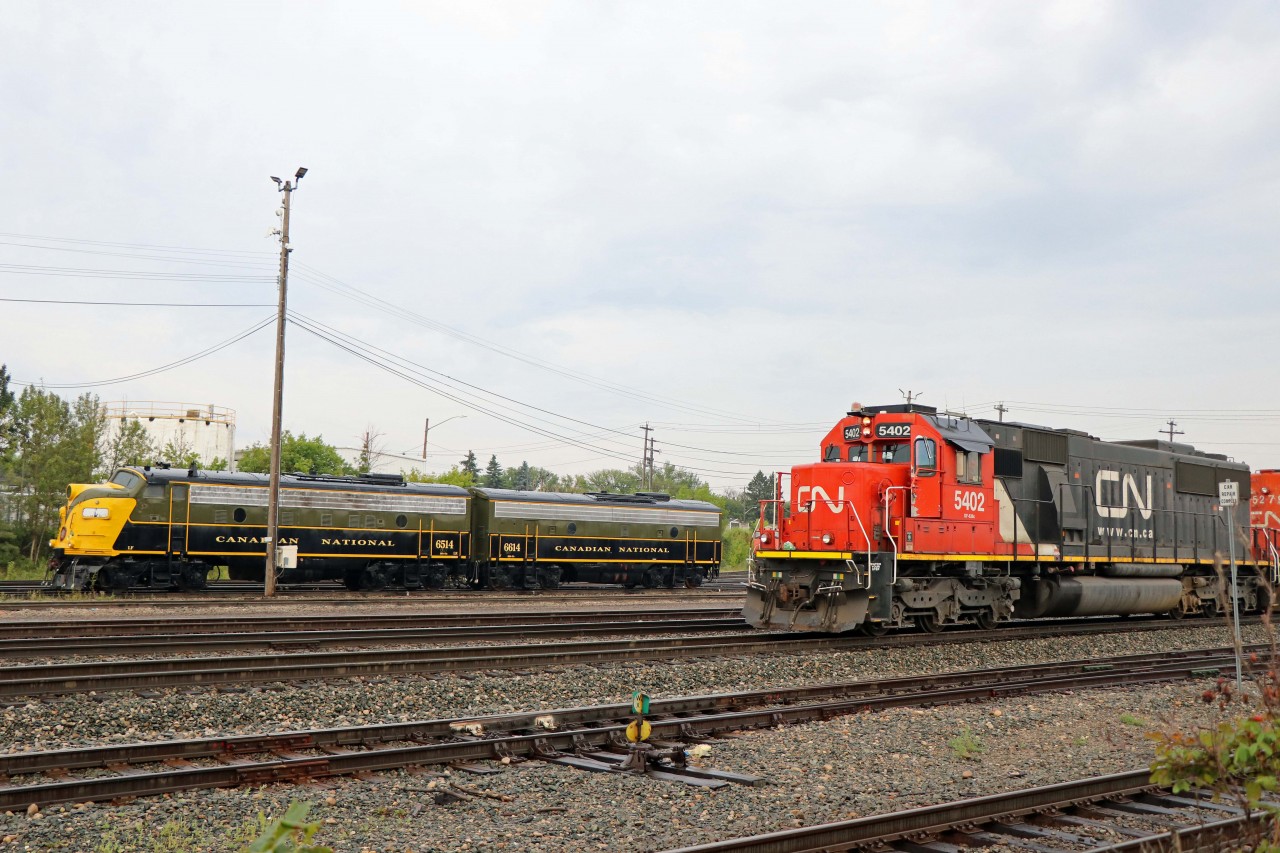 On a rainy Sunday morning, a CN yard assignment (powered by SD60 5402 and SD40-2W 5279) shuffles cars at West Jct near Walker Yard as preserved units 6514 and 6614 look on. Now owned by the Alberta Railway Museum, these F units have an interesting history--they were built for CN in 1957, acquired by VIA in 1978, later sold to the Algoma Central (numbers 1753 and 1762), and retired again in 2001 before being donated the Museum in June 2003. They will be exhibited at the "Christmas in the Rockies!" charity event in Jasper on 2 August 2025 (11:00 AM to 5:00 PM, Jasper CN station).