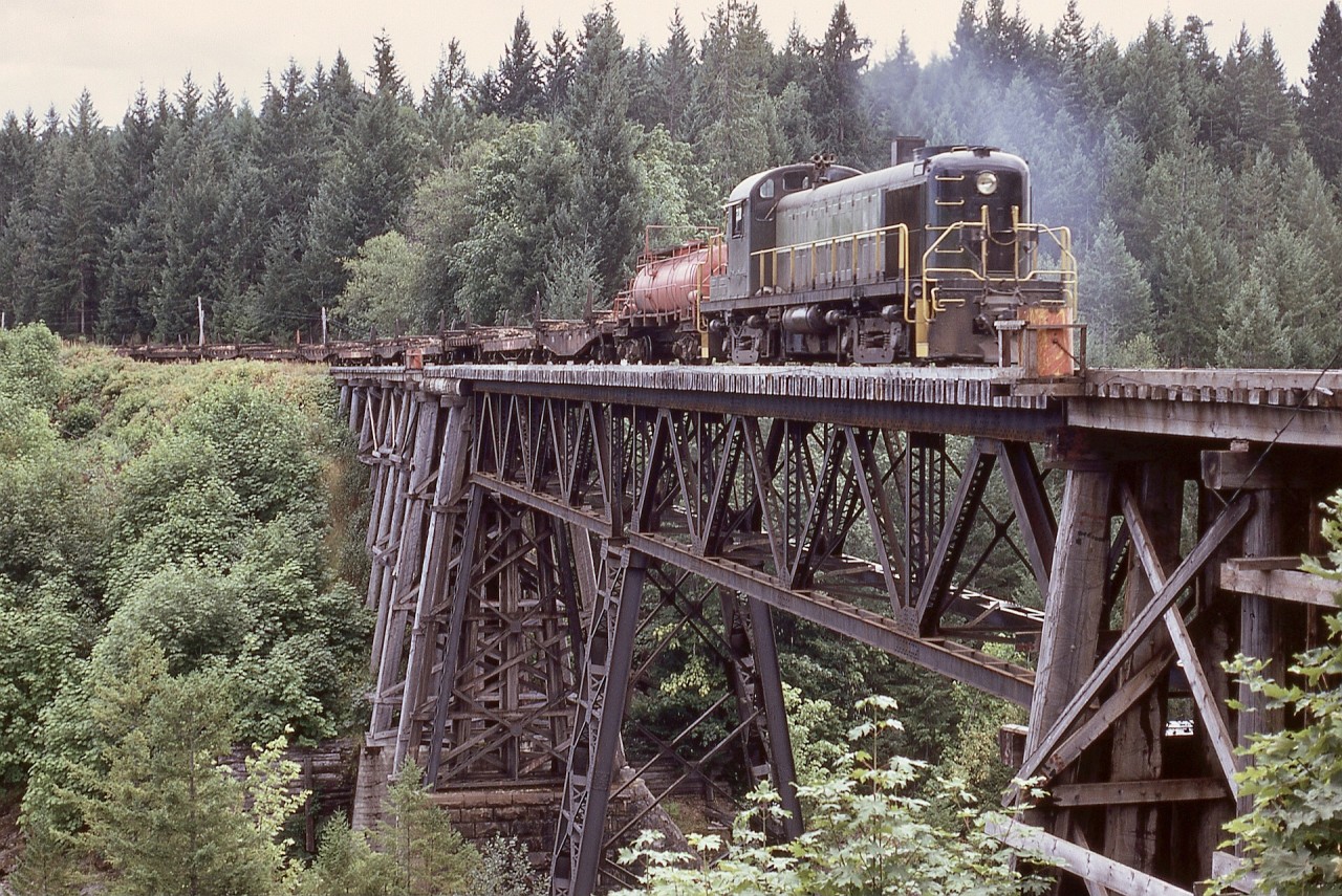 When Crown Zellerbach at Ladysmith acquired ALCo RS-3 4097 via United Railway Supply, it had been painted in a two-tone green scheme thought to be part of a sales pitch to British Columbia Railway, and was run in that livery for three months before repainted in the bright CZ orange with white stripes scheme.  This view is westbound on Wednesday 1973-08-22 with empties over the same Nanaimo River bridge in two other recent posts by me.  Please overlook that confounded water barrel platform!