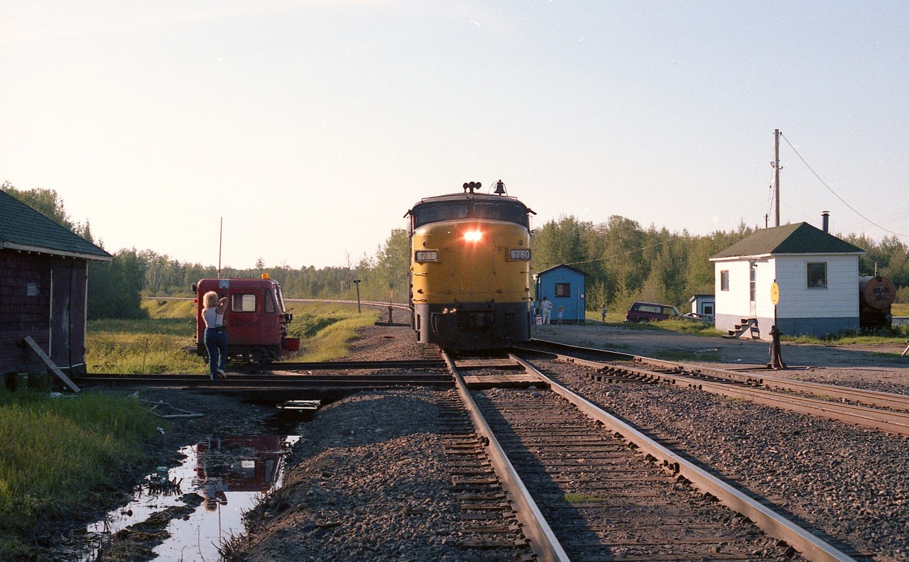 One of those places nobody visits.  Well, almost nobody. I posted a shot from here once before, however this more head on image has a little more detail.
Smooth Rock was where the Mattagami Railroad used to connect with the ONR. It was a 3 mile line that serviced the Abitibi operations in Smooth Rock Falls.  All of that operation, including the railroad, is now history.
In this image, eastbound VIA 6760 with two cars has stopped at the Smooth Rock "station" (blue building) and a couple of passengers are boarding. Lets presume they are going into Cochrane and might transfer to the Ontario Northlander which is the connection to Toronto. (Both this train and the Northlander no longer operate.)
In the scene on the right is the railroad's "office". The track on the right a connection to the Mattagami. On the left is a section shack with Fairmont motor (built 1976) out front, and my Sidekick of the day taking backup photos in case of any problems. After all, this is not particularly a place I wanted to visit very often. The evening mosquitos were ferocious, to put it mildly. And this was at sundown.