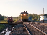 One of those places nobody visits.  Well, almost nobody. I posted a shot from here once before, however this more head on image has a little more detail.
Smooth Rock was where the Mattagami Railroad used to connect with the ONR. It was a 3 mile line that serviced the Abitibi operations in Smooth Rock Falls.  All of that operation, including the railroad, is now history.
In this image, eastbound VIA 6760 with two cars has stopped at the Smooth Rock "station" (blue building) and a couple of passengers are boarding. Lets presume they are going into Cochrane and might transfer to the Ontario Northlander which is the connection to Toronto. (Both this train and the Northlander no longer operate.)
In the scene on the right is the railroad's "office". The track on the right a connection to the Mattagami. On the left is a section shack with Fairmont motor (built 1976) out front, and my Sidekick of the day taking backup photos in case of any problems. After all, this is not particularly a place I wanted to visit very often. The evening mosquitos were ferocious, to put it mildly. And this was at sundown.