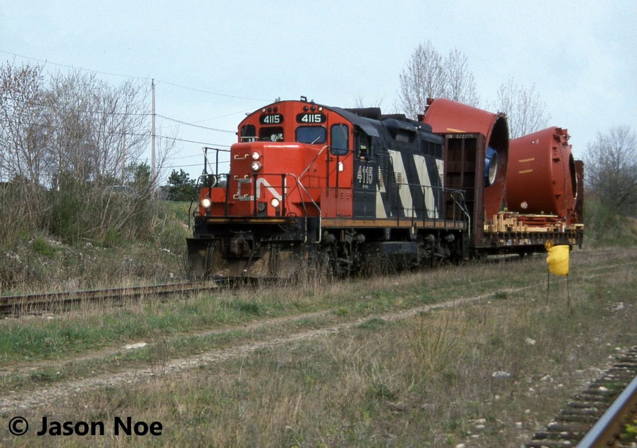 CN 580 with GP9RM 4115 is viewed approaching the Concession Road crossing in Cambridge, Ontario after lifting a loaded bulkhead car from the Babcock & Wilcox facility on the Fergus Subdivision. The crew had just set-off an empty flat car at the plant and were heading to continue switching industries on the Galt Industrial Spur in Cambridge. To the bottom right is the CP Waterloo Subdivision, which paralleled the Fergus Subdivision here to the CN Finnigan sign near Hespeler Road.