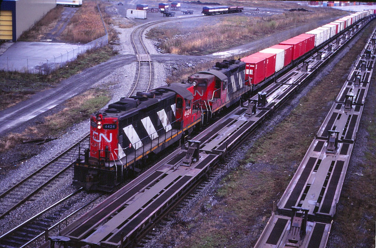 A transfer from the Port of Montreal arrives at MonTerm, on the site of CN's old Turcot Yard (which was the major yard in Montreal until Montreal Yard--now known as Taschereau Yard--opened in September 1961). Turcot subsequently became a piggyback and container terminal until September 2002 when intermodal operations where moved to the newly constructed Montreal Intermodal Terminal at the reconfigured Taschereau Yard (the hump having been shut down). Today, Turcot continues to act as a crew change point for through trains bypassing Taschereau. Back to that transfer with GP9s 4424 and 4416--note that the latter unit has some GP7 battery box louvres and still has an "oil can" headlight, which early GP9s were delivered with. And, for those of you who have always wondered where the "Dofasco steel containers" went after leaving Hamilton, the Montreal unloading facility is in the background (hence the placement of the container flats at the rear/west end of Hamilton-Montreal train 252).