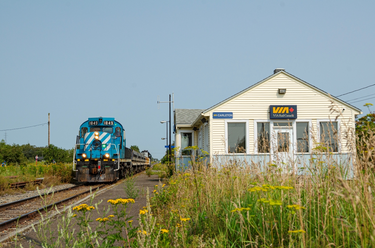 To help fighting coastal erosion, the provincial government allocated a 25 Million dollars contract to replenish the beaches in the small town of Maria, in eastern Quebec. To help fighting vehicular traffic on Route 132, the railway was chosen to carry the crushed stones from a quarry in Nouvelle, to the beaches of Maria. These operations consists of about 6 round trips a day. One with a train made of 7 Diffco side-dump cars and one locomotive at each end, and another made of multiple modified 2-bay cement hoppers, four ex-UP ballast cars along with 2 locomotives at the head end and one at the rear end, in order to return the empty train back to Nouvelle. This longer train only operates twice a day, once in each direction.

These operations should last until December 2025, and they make for a nice opportunity to catch SFG's fleet of RS18us, as a large part of their roster is needed to conduct these operations.

In this picture we can see one of the empty return trips of the shorter train, led by RS18 #1849 and ending with HLCX 1069, passing by the old VIA Rail Carleton station. It has been abandonned since VIA Rail discontinued the Chaleur trains, due to the line past of New Richmond being in disrepair. It is unknown when service will resume.