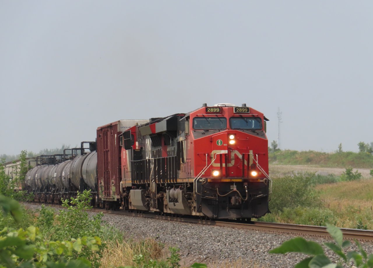 Smoky skies conceal the usual dust cloud from the adjacent Lafarge quarry as a southbound mixed freight approaches the second concession of Ramara.