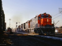 Rumbling over the Weston Road crossing on approach to West Toronto diamond, CN extra 5552 east, possibly a <a href=https://www.railpictures.ca/?attachment_id=42775>"Limehouse Turn" from Indusmin's quarry at Limehouse,</a> passes through the junction behind an SD40 and triple set of GP9s.
<br><br><i>Scan and editing by Jacob Patterson.</i>