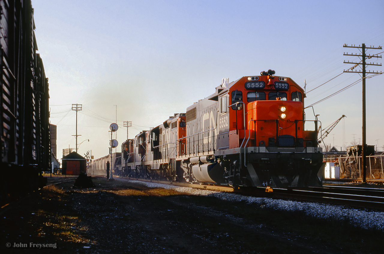 Rumbling over the Weston Road crossing on approach to West Toronto diamond, CN extra 5552 east, possibly a "Limehouse Turn" from Indusmin's quarry at Limehouse, passes through the junction behind an SD40 and triple set of GP9s.
Scan and editing by Jacob Patterson.