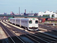 An eastbound GO train from Oakville approaches Union Station, just past Spadina Avenue.  GMD GP40TC 503 pushes on the rear.  In the distance, CNR 6060 has just departed for Niagara Falls, passing under Bathurst Street.

<br><br><i>Scan and editing by Jacob Patterson.</i>