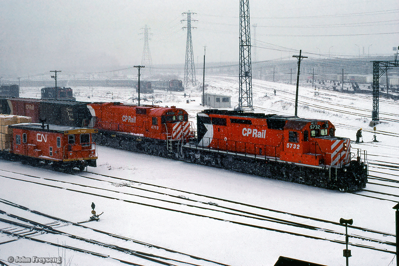 A westbound CP Rail movement makes its way through the activities underway around the Toronto Terminal Railways trackage at Bathurst Street.  A CN transfer van sits at left, while switch tenders clean switches in the background for the four MLW S13 coach yard switchers.

Scan and editing by Jacob Patterson.