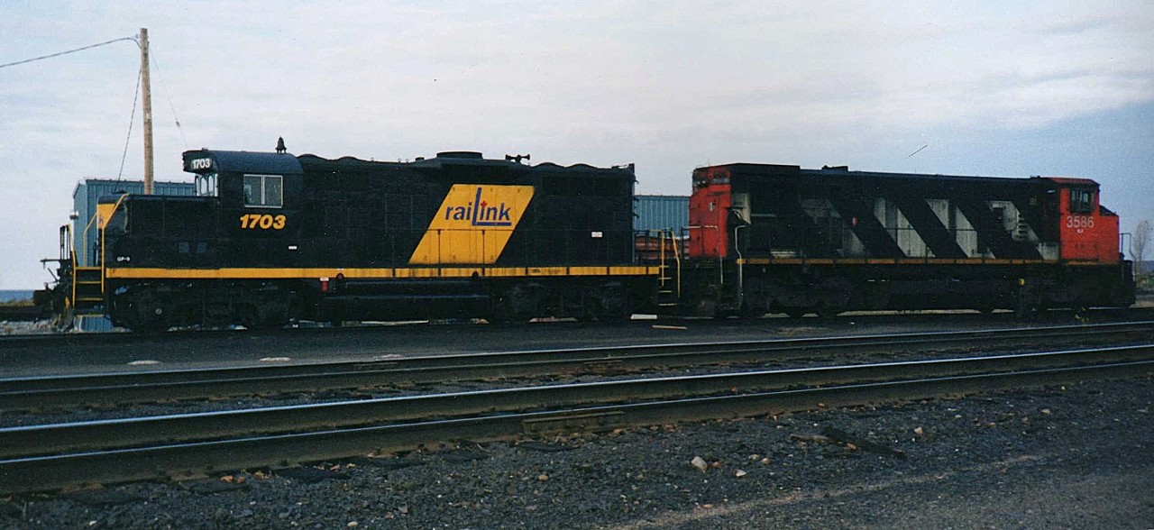 Where's my notebook  
RLK 1703 & RLK 3586 sit idle on the engine track in RaiLink's shop complex at North Bay, ON in this early to mid-1990's shot.