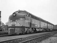 Behind a pair of lightning-striped EMD E8As, train 50, the eastbound <i>Empire State Express,</i> roll into St. Thomas at 10:25h if on time.  Lots of headend traffic makes up nearly half of this train.  At left, pieces of work equipment can be seen, including the tip of a wedge plow, and a small flatcar with parts atop it.  At right, the electrified connecting track of the <a href=https://www.railpictures.ca/?attachment_id=56761>London & Port Stanley Railway, </a>running from the north side of the CASO station, west towards <a href=https://www.railpictures.ca/?attachment_id=55666>BX Tower,</a> just visible in the distance, where it would swing north to connect with the L&PS mainline.

<br><br>At left is the St. Thomas water tower, built in 1914, and holding the title of Canada's largest steel water tower, and second largest steel tank in North America.  It was demolished in 1993.   Photos taken from the tower in 1975 show various scenes of the town, including the railway.  <a href=https://jimstewart360.ca/places/view-from-the-st-thomas-watertower-1975/>Take a look at these pics here.</a> 

<br><br><i>Original Photographer Unknown, Jacob Patterson Collection Negative.</i>