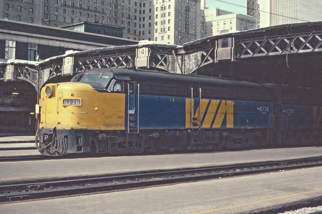MLW FP4A 6776 is seen at the west end of Toronto Union Station on Track 5 ready to head west with a Via passenger train in July of 1982. The imposing Royal York Hotel is seen looming above the trainshed, with the gold-colored Royal Bank tower just to the right of the hotel. What a great place to watch and photograph trains way back then!