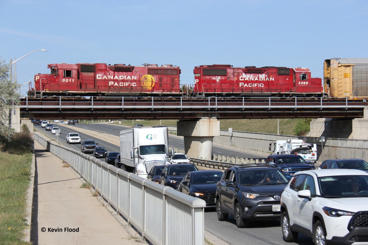 CPKC H70 does its usual switching in/around Maple Grove/Toyota plant as it passes over a busy Maple Grove Rd at the border of Kitchener and Cambridge. The train would proceed in reverse to switch the plant at Fountain St. Power is CP 3011-3099. Nice to see some older models working. There was a time when this crossing was at grade. A bridge was definitely a good call as this was a traffic nightmare. I wonder if anyone has any shots here when it was a level crossing.