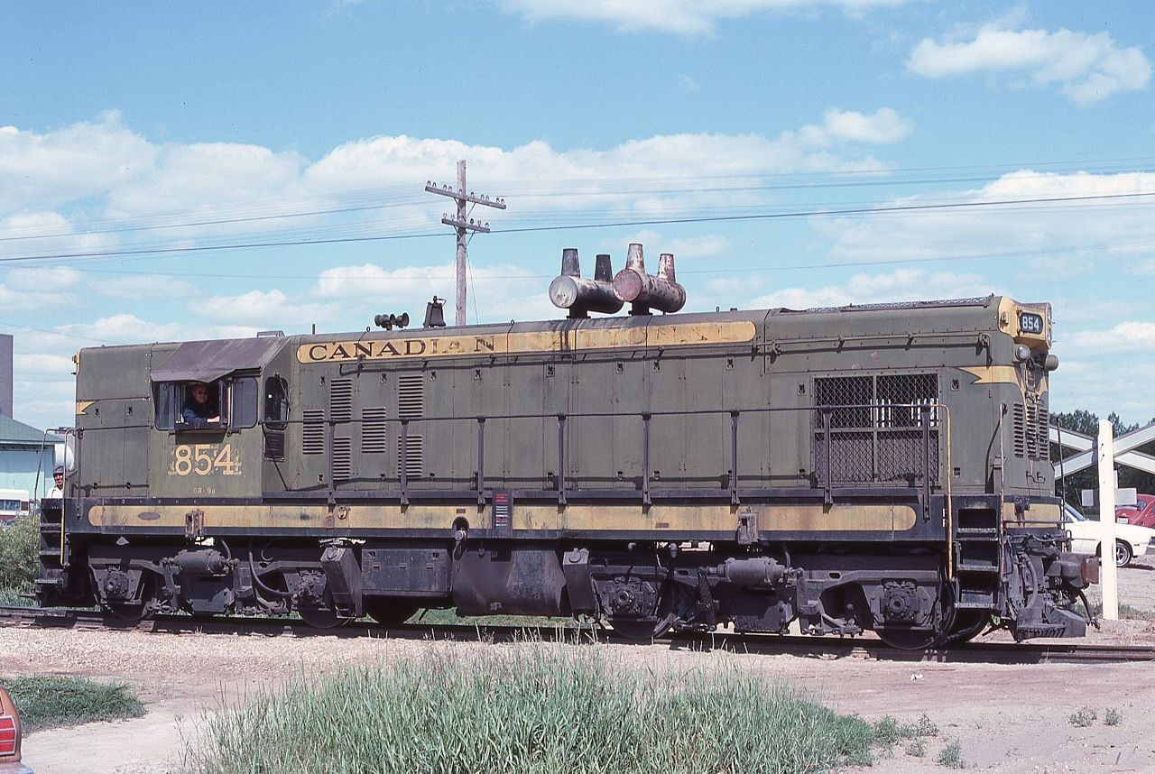 CN G8 854 pauses for its picture in Yorkton, SK on June 20, 1978.  The unit was delivered to CN in June 1954 as 7674, renumbered a number of times to 1574, then to 1104, and finally to 854.  One has to wonder what CN was thinking when this group of 5 units (850-854) was ordered as CN had already received all their F7s, GP7s, and many yard units by this time and GP9s, SW1200RSs, and FP9s were only a couple of months out. These export style units seemed destined to become standard gauge orphans.  

Location in Yorkton is a guess.