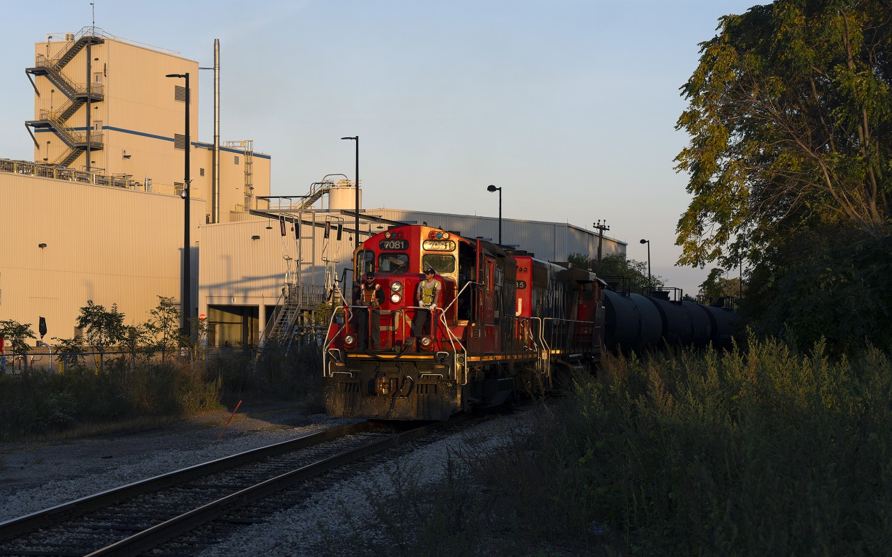 CN's 1600 yard job out of Stuart Street pulls up to Victoria Avenue on their way back to homebase as the sun begins to sink towards the horizon, bathing GP9RM 7081 in golden evening light. The Bunge facility is the white building in the background.