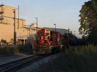 CN's 1600 yard job out of Stuart Street pulls up to Victoria Avenue on their way back to homebase as the sun begins to sink towards the horizon, bathing GP9RM 7081 in golden evening light. The Bunge facility is the white building in the background.