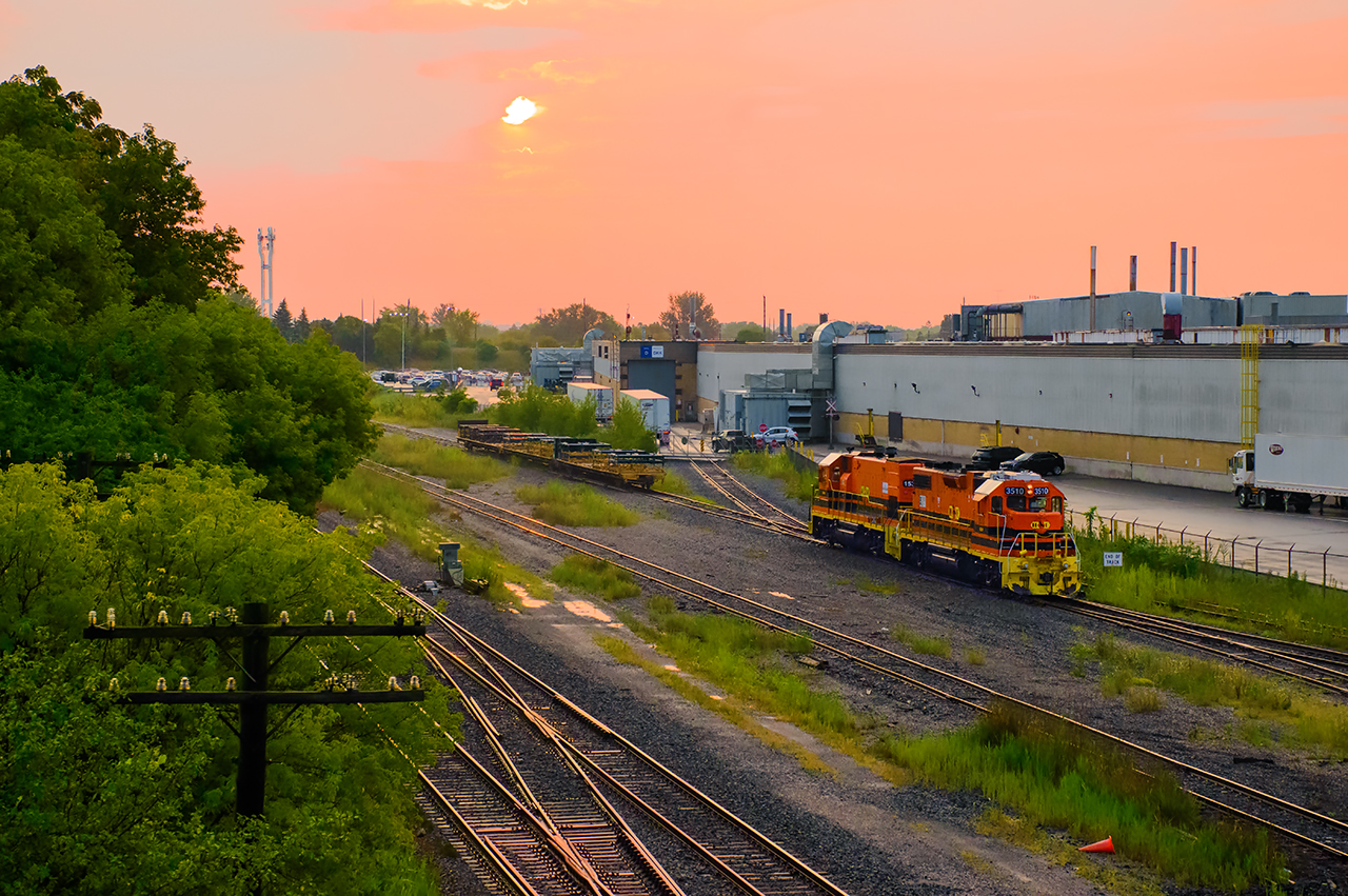 The morning sun rises over GM Oshawa, where G&W's Railsynergy job has just finished spotting frame loads inside the plant.  Shortly, they will spot the empties back in the CN yard, before running down the General Motors Lead to lift loaded racks.