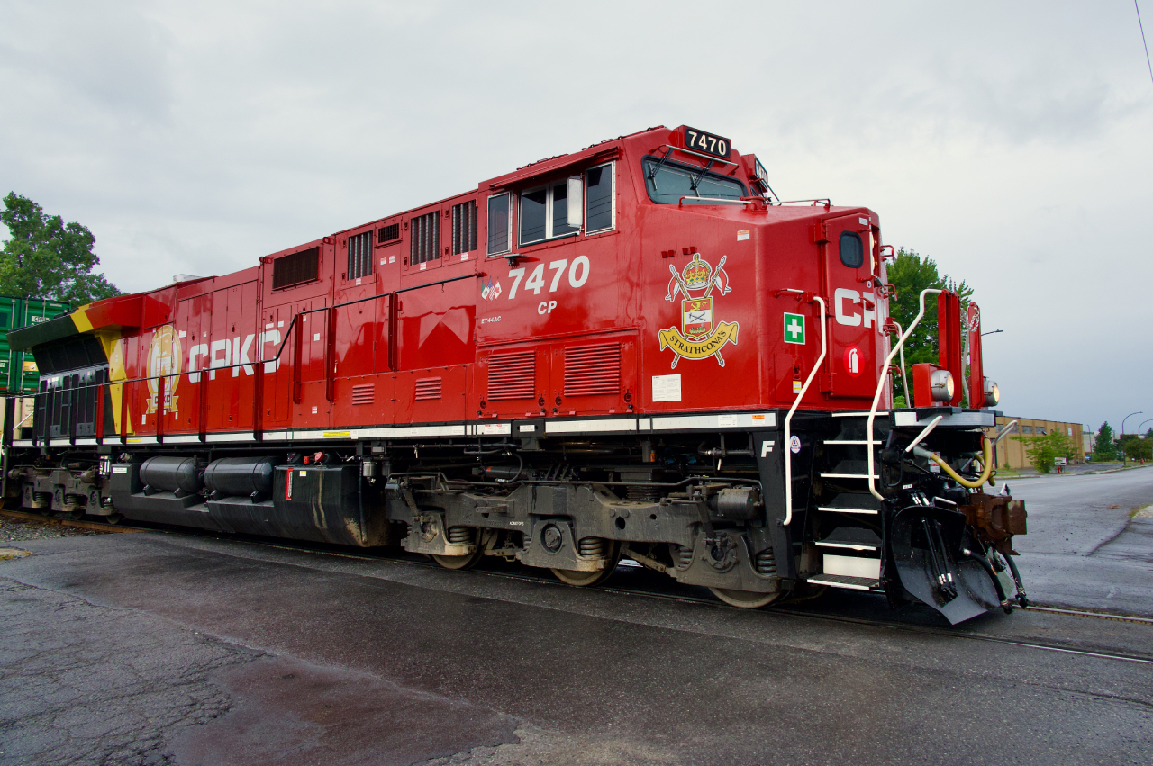 Fresh CP 7470 leads CPKC 112 over a crossing as it approaches Lachine IMS Yard on a rainy morning. CP 7470 features a logo honouring the Lord Strathcona's Horse (Royal Canadians) armoured regiment.