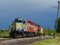 CN 538 is returning from Valleyfield with just two cars as the sun shines through on a mostly rainy afternoon. IANR 4100 leads.