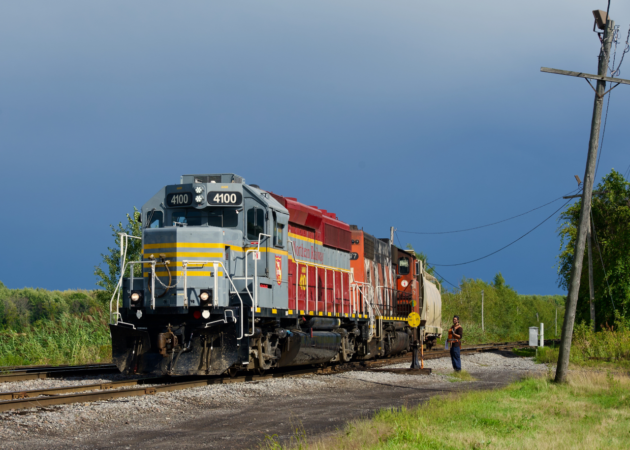 CN 538 is returning from Valleyfield with just two cars as the sun shines through on a mostly rainy afternoon. IANR 4100 leads.