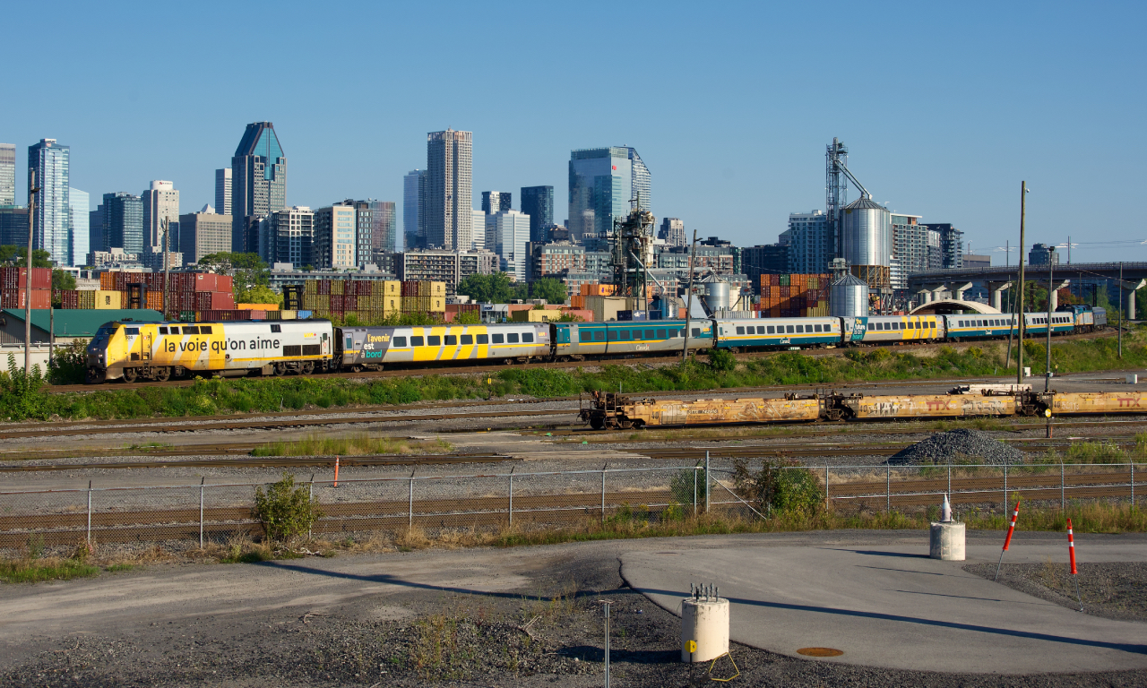 VIA 63 has an F40 and a HEP coach deadheading on the rear as it passes the skyline of downtown Montreal.