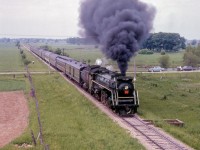 Black coal smoke blasts high above the farmland near Milverton as an Upper Canada Railway Society excursion behind CNR U-2-e 6167 is seen along the Newton Sub, about to duck under CPR's Goderich Sub.  The train, carrying over 500 passengers, travelled from Toronto - Dundas - Lynden - Guelph - Palmerston - Stratford - Kitchener - Georgetown - Toronto.

<br><br>More scenes from this trip:
<br><a href=https://www.railpictures.ca/?attachment_id=54890>Drayton</a>
<br><a href=https://www.railpictures.ca/?attachment_id=52876>Peffers</a>

<br><br><i>Scan and editing by Jacob Patterson.</i>