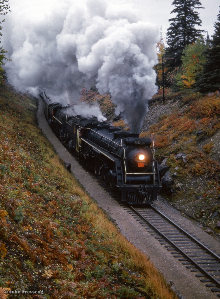 Storming south at the aptly named Wooden Bridge Road, a doubleheaded excursion behind CNR 4-8-4s 6167 and 6218 are about to pass beneath the wooden bridge, returning to Toronto.  This was the first of two trips operated by the Upper Canada Railway Society during the Sept. 26-27 weekend, marking the retirement of CNR 6167, and the excursion role being assumed by CNR 6218.  Departing Toronto Union Station, and carrying over 900 passengers, the excursion operated via Beaverton to Scotia Junction, turning on the wye with the Algonquin Sub, and back south via Allandale.  Sunday's trip operated Toronto - Dundas - Paris - Caledonia - Hamilton - Toronto with over 400 passengers.

Scan and editing by Jacob Patterson.
