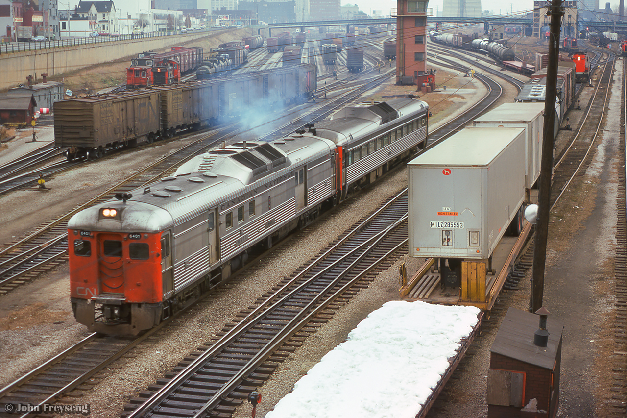A westbound set of Budd cars accelerate through the busy Toronto Terminals Railway trackage west of Union Station.  An eastbound freight waits at a red signal beneath Spadina, while n SW1200RS works in the Bathurst North Yard, while at right, assorted passenger and yard power can be seen, including a Tempo RS18m, F units around the coaling plant, MLW S13s working the coach yard assignments, and a GM switcher at far right.

Scan and editing by Jacob Patterson.