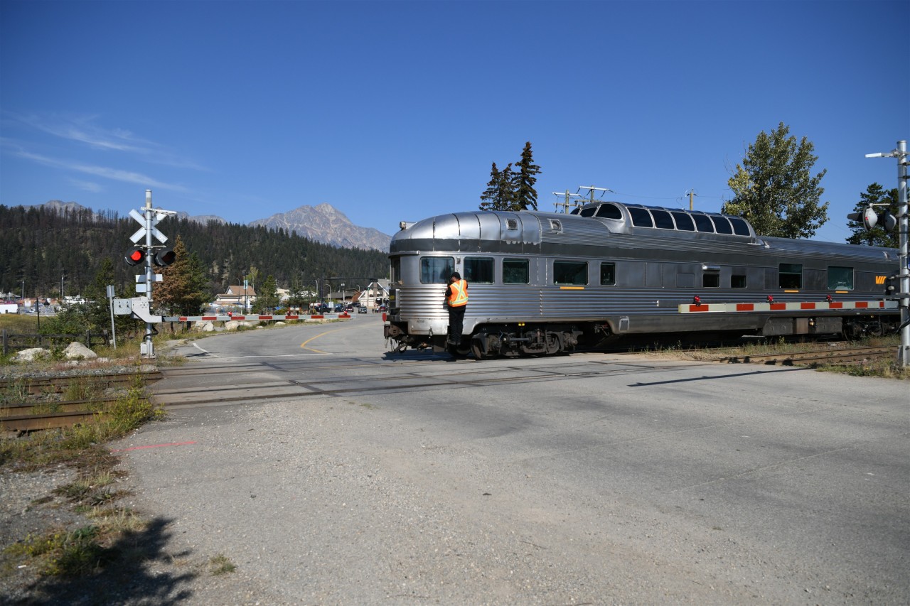 Westbound VIA No. 2 ... Is that possible  
VIA 002 The Canadian with VIA 88708 Jasper Park leading is heading west out of the station track in Jasper on this beautiful September morning. 
With major track realignment and other construction work at the east end of CN's Jasper yard, it was necessary for VIA No. 2 to complete its normal station stop and servicing, then make a reverse move from the station track and head west to CN Home at Mile 0.5 on the Albreda Sub. before resuming its eastward journey to Edmonton, Winnipeg, and Toronto. 
Under the watchful eye of the second engineer, the movement rolls across Hazel Avenue crossing at the west end of CN's Jasper yard.