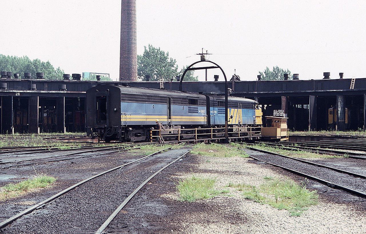 Via Rail MLW locomotive FP4A 6789 leads MLW FPB4 6867 onto the turntable at the old Via roundhouse on a hot summer day in August of 1983, back when roundhouses were still a thing. All of this is changed nowadays, although I am told you can visit a great museum and get food and ale at the former CP John Street location. Note the sign stating, "All units must stop before coming on turntable.' They indeed did stop on that day, way back when.