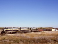 To supply traffic to CN’s Great Slave Lake line, Northern Alberta Railways ran a daily trip from McLennan to CN Roma Jct. near Grimshaw, and regular power was three of NAR’s four SD38-2 units, dynamic brake equipped for the grades down to and up from a crossing of the Peace River at the town of the same name.  On Sunday 1980-09-28 at the south end of CN’s yard, NAR 402 + 403 + 404 on a GSL Turn are assembling their train (concentrate loads on the headend) for the return to McLennan under a gloriously clear Peace River country sky.

<p>This is all CN territory now, and the SD38-2s have moved elsewhere.
