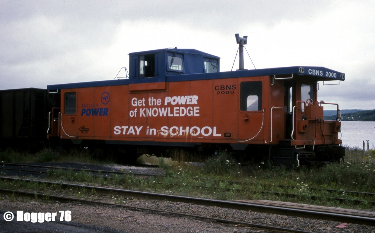 Cape Breton & Central Nova Scotia Railway (CBNS) caboose # 2000 is pictured sitting in the community of Port Hastings, which is situated on the southwestern tip of Cape Breton Island, Nova Scotia. The van was former CN 79509 and was used frequently by CBNS crews at the time. Today, photos online and a satellite view show this van still stored on CBNS property on a siding at Afton Station.
