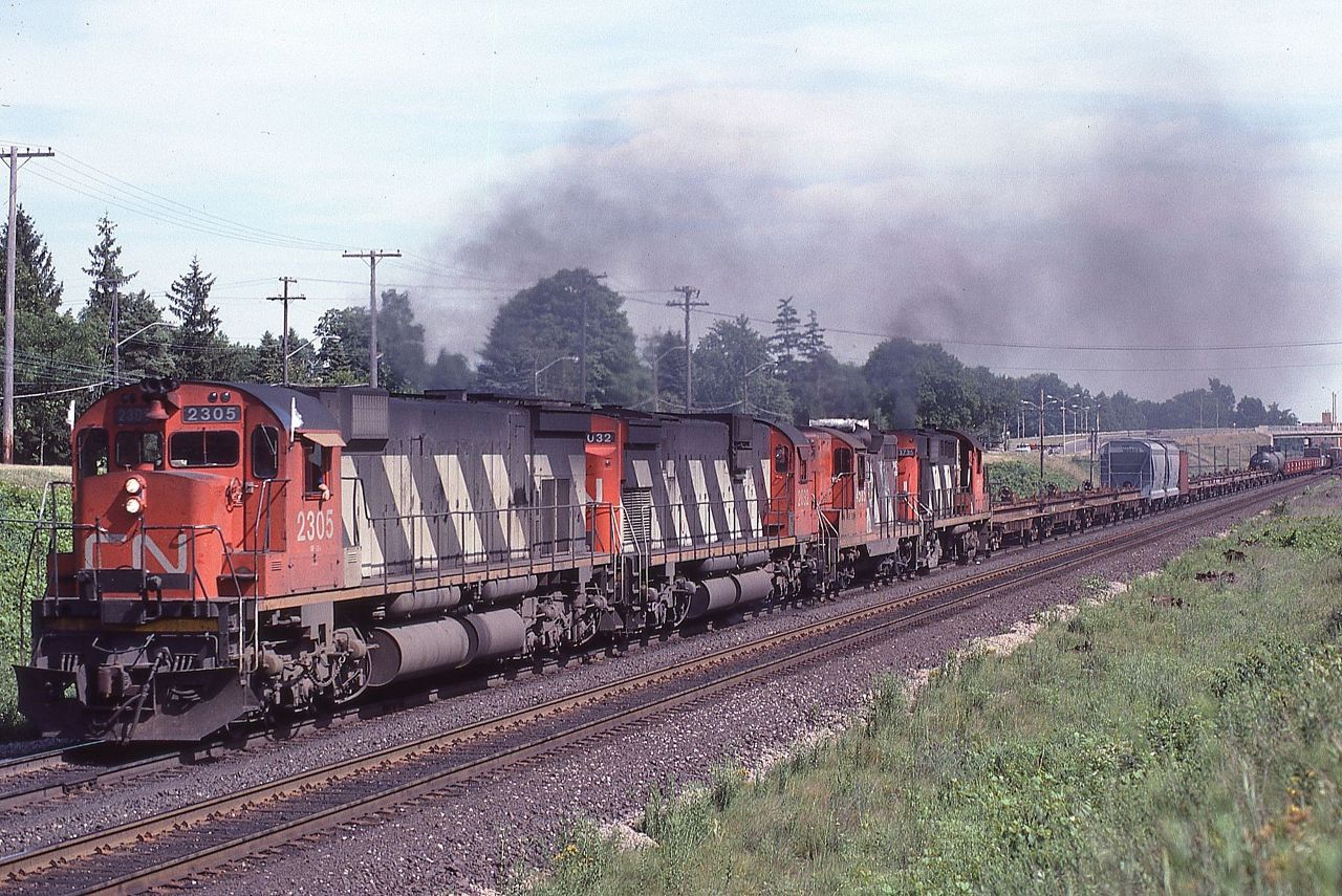 CN 2305 leads a westbound train with 111 cars out of Brantford, Ontario on July 11, 1981.  The consist was: M636 2305, C630 2032, GP9 4585, and RS-18 3735.  Lots of noise and exhaust!  Those were the days!!!