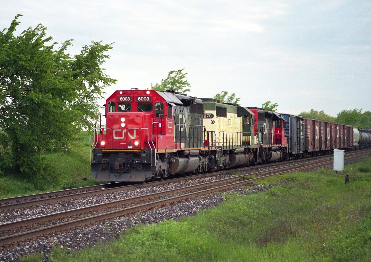 Westbound at Tansley on a pleasant June day...remanufactured CN SD40U locos 6003 and 6007 sandwich an NRE 807 for power as the train comes up to #1 Sideroad. My map indicates the north side of the road is Milton, the south side, Burlington. I've always referred to this area by the old name, Tansley. This was an enjoyable place to hang out back then, when everything was quiet but the railroad.
Image shot with Mamiya 645 film camera with 400 ISO Fuji Reala for those interested.