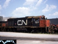 During a summer afternoon in 1987, shop crews are preparing to move GP38-2 7507 (former CN 5555) and its slug mate from the CN MacMillan Yard diesel shop in Vaughan, Ontario. Other power is seen in the background around the shop awaiting attention. 