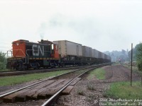Hamilton-assigned CN S4 8170 handles a cut of loaded piggyback flatcars and caboose, heading eastbound through Hamilton Junction towards Bayview Junction on the Oakville Sub. The cowpath connecting track is visible in the foreground (Hamilton Jct-Hamilton West). This was noted by Bill as a "van turn" move, IIRC this was a yard job from nearby Stuart St. Yard sent out to Bayview to wye the piggyback flats so the trailers/vans would be facing the correct way for "circus-unloading" (i.e. backing a truck over the cars to hook up and unload each trailer separately) at the piggyback ramp in the yard. And since the junction was just one big wye, it was probably the most convenient spot for it.<br><br>In the background on CP trackage is CP GP35 5002 and RS18 8788 handling a dimensional train with <a href=http://www.railpictures.ca/?attachment_id=39073><b>Ontario Hydro schnabel car HEPX 200</b></a>, waiting to head up the Goderich Sub.<br><br><i>Bill McArthur photo, Dan Dell'Unto collection slide.</i>